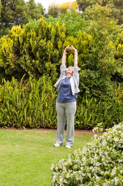 Donna pensionata che fa i suoi streches nel giardino