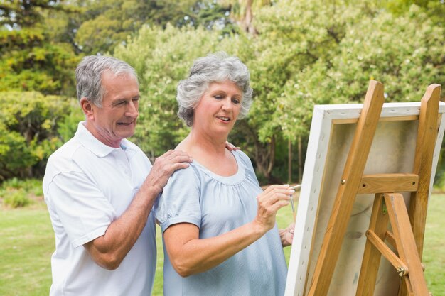 Donna pensionata pacifica che dipinge su tela con il marito