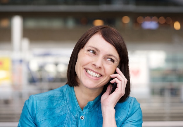 Donna più anziana che sorride quando parla sul telefono cellulare