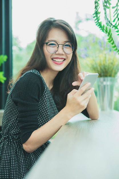 Donna più giovane asiatica che ride con emozione di felicità leggendo smart phone