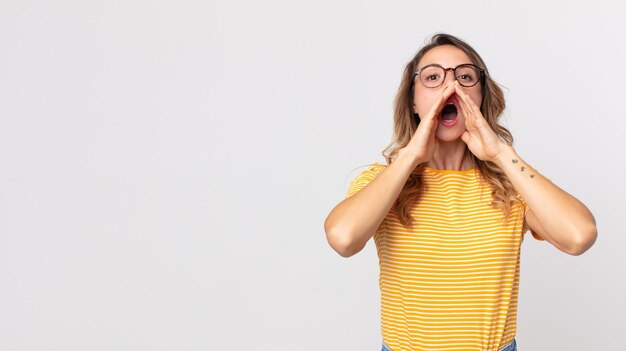 Donna piuttosto magra che si sente felice, eccitata e positiva, emette un grande grido con le mani vicino alla bocca, chiamando