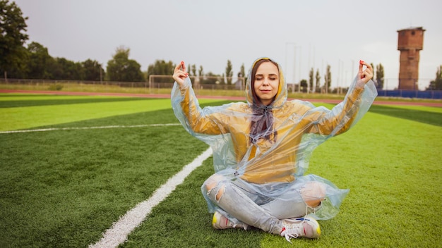 Donna positiva che medita con gli occhi chiusi sul campo sportivo