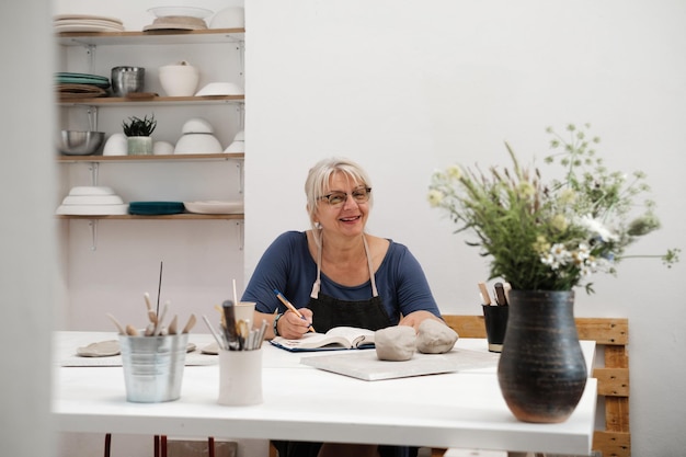 Donna potter scrivendo al tavolo Pianificazione attività creative