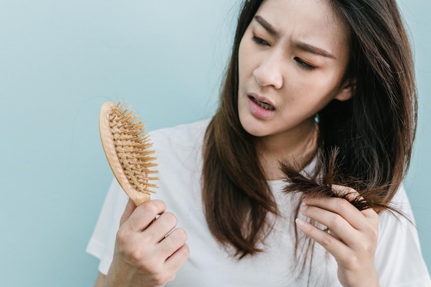 Donna preoccupata che tiene il pennello con i capelli sullo sfondo blu