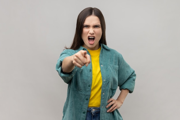 Donna prepotente arrabbiata con i capelli scuri che punta alla telecamera con un'espressione aggressiva che fa una scelta