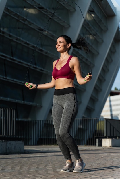 Donna propositiva motivata in abbigliamento sportivo che fa esercizi di salto con la corda durante la mattinata di sole sulla pista dello stadio Concetto di pratica sportiva e di salute