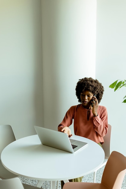 Donna radiosa che conversa al telefono mentre lavora in un caffè luminoso