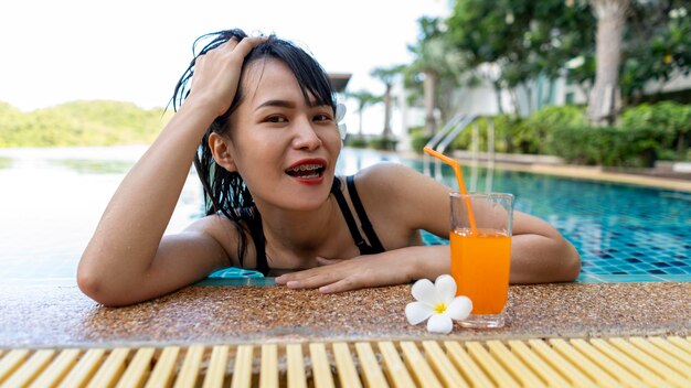 Donna relax con succo d'arancia in piscina durante le vacanze di tempo libero