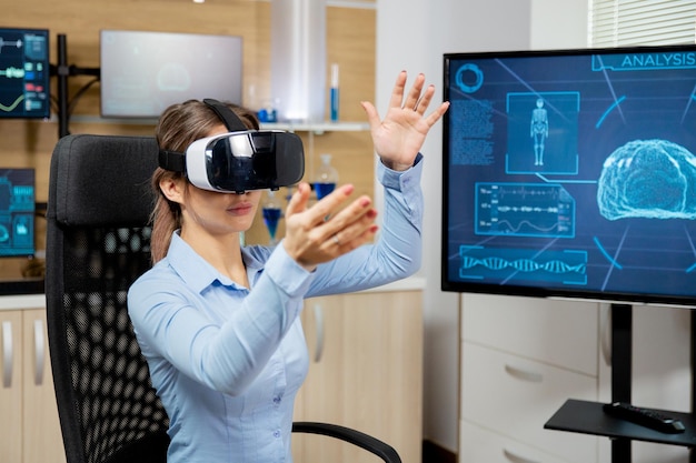 Donna residente che esplora la realtà virtuale in un laboratorio scientifico. Equipaggiamento moderno