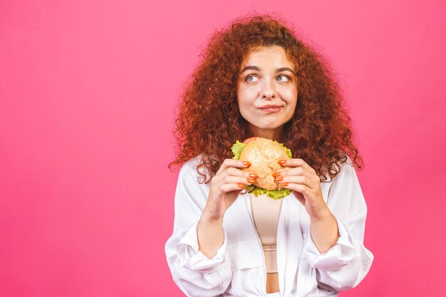 Donna riccia che mangia un hamburger