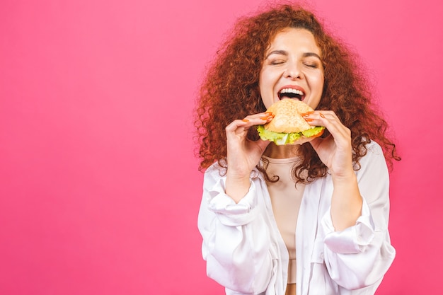 Donna riccia che mangia un hamburger