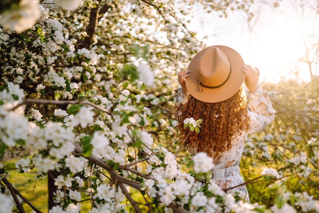 Donna riccia con il cappello in posa nel romanticismo del parco primaverile e nelle vacanze primaverili