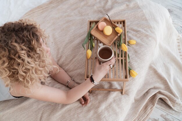 Donna riccia sveglia che fa colazione a letto