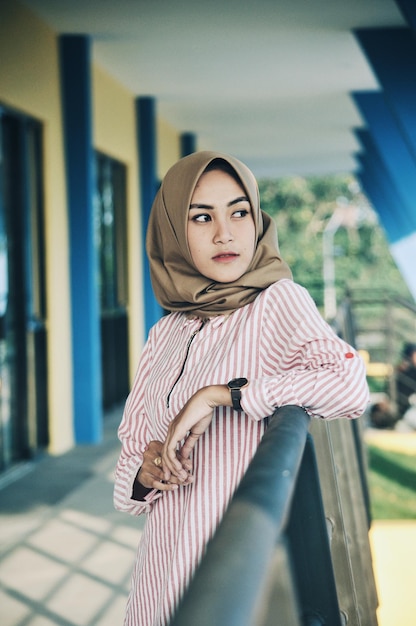 Donna riflessiva che indossa l'hijab mentre si trova accanto alla ringhiera