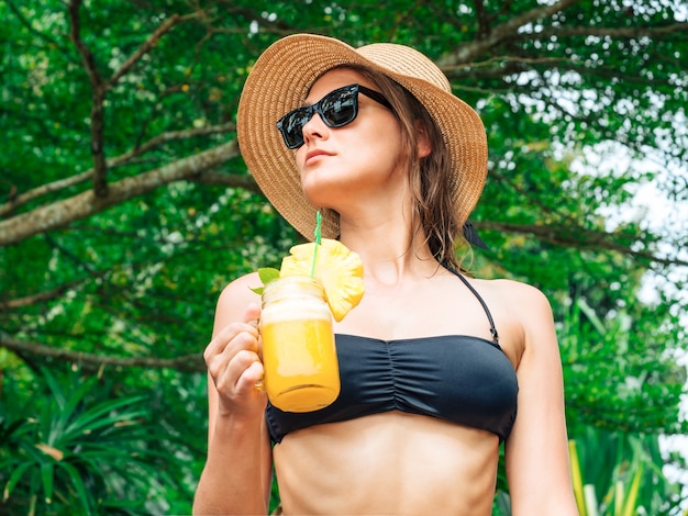 Donna rilassata in bikini godendo resort tropicale, bevendo cocktail di ananas