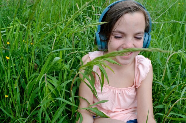 Donna rilassata sdraiata sull'erba che ascolta musica con le cuffie in un parco