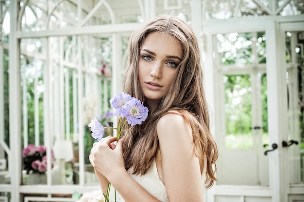 Donna romantica con fiori. Bellissima modella con capelli castani e trucco naturale