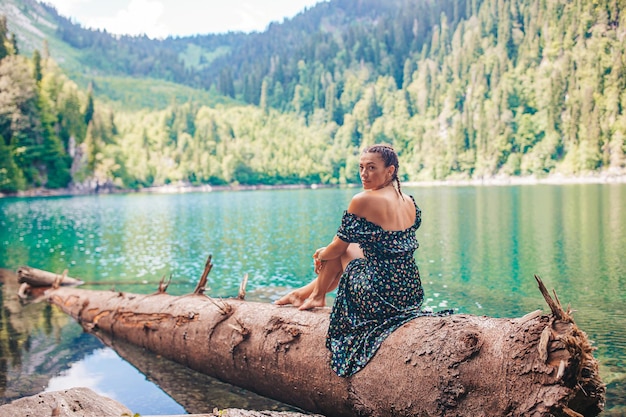 Donna romantica felice che si siede dal lago che spruzza acqua