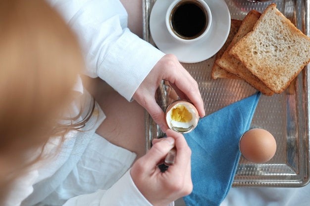 Donna rossa che mangia colazione a letto nella camera d'albergo