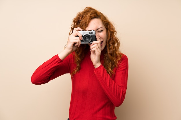 Donna rossa con maglione dolcevita in possesso di una macchina fotografica