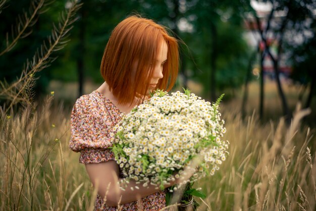 Donna rossa di quarant'anni con un grande mazzo di fiori di campo in estate nella natura