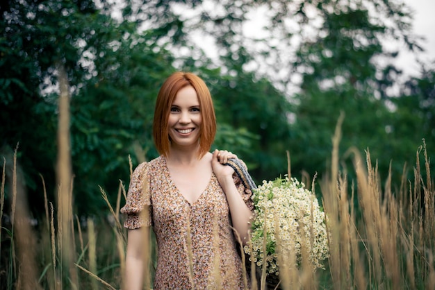 Donna rossa di quarant'anni con un grande mazzo di fiori di campo in estate nella natura