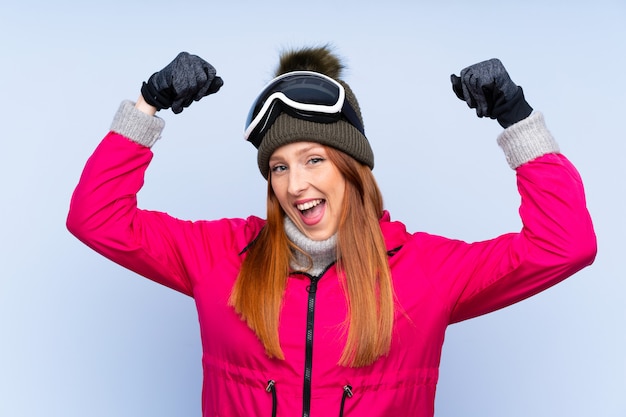 Donna rossa sciatore con occhiali da snowboard che celebra una vittoria