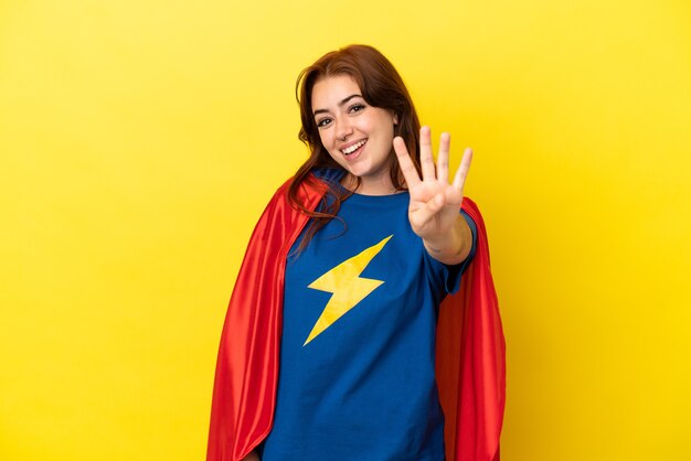 Donna rossa super eroe isolata su sfondo giallo felice e contando quattro con le dita