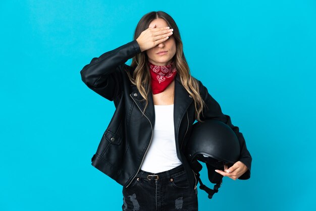 Donna rumena che tiene un casco del motociclo isolato sugli occhi blu della copertura murale con le mani. Non voglio vedere qualcosa