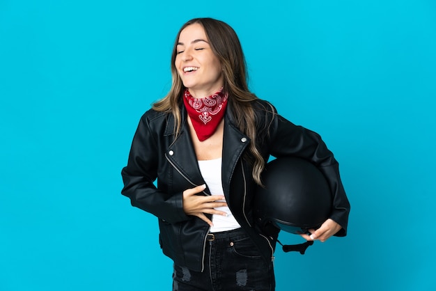 Donna rumena che tiene un casco del motociclo isolato sull'azzurro che sorride molto