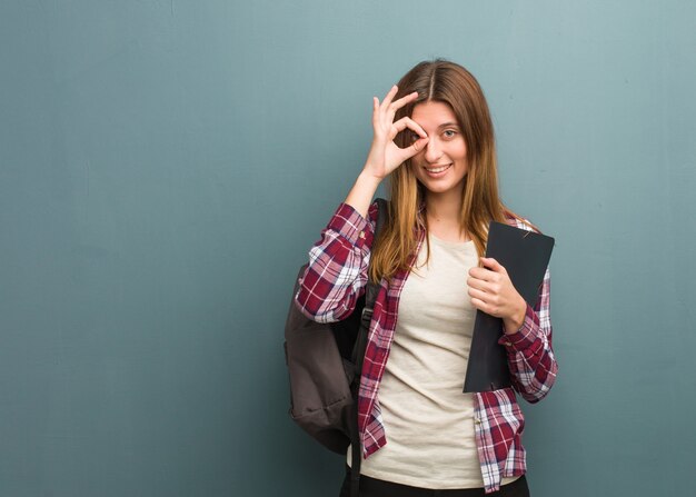 Donna russa del giovane studente fiduciosa che fa gesto giusto sull'occhio