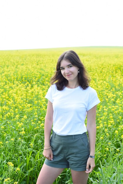 Donna russa in piedi nel campo di colza e guardando la telecamera