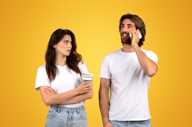 Donna scettica con una tazza di caffè che guarda un uomo sorridente che parla al cellulare