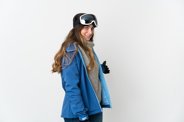 Donna sciatore con occhiali da snowboard isolato su bianco che estende le mani a lato