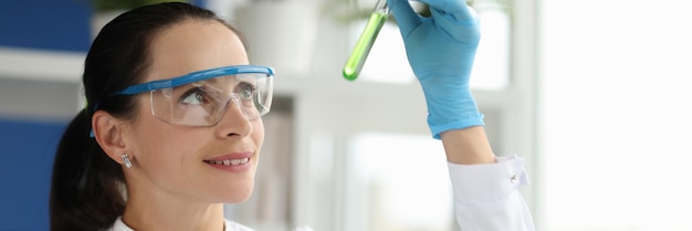 Donna scienziato chimico guardando la provetta con liquido verde in laboratorio farmaceutico