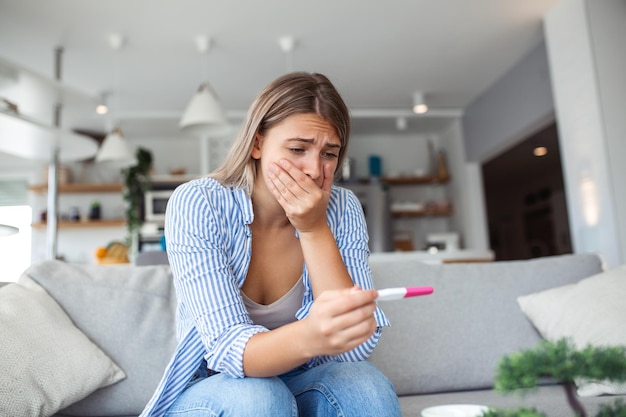 Donna scioccata che guarda la linea di controllo sul test di gravidanza Singola donna triste che si lamenta in possesso di un test di gravidanza Donna depressa con test di gravidanza negativo