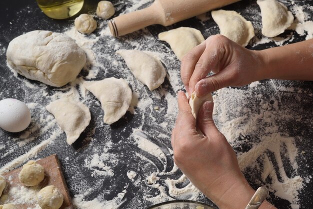 Donna scolpisce gnocchi con patate fatte a mano su sfondo nero Girato dall'angolo superiore Cucina popolare ucraina