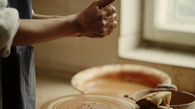 Donna sconosciuta che scolpisce argilla in ceramica Mani di donna non riconosciute che modellano un pezzo di argilla in laboratorio