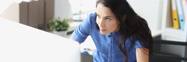 Donna scontenta sorpresa che guarda il monitor del computer sui problemi aziendali sul posto di lavoro e male