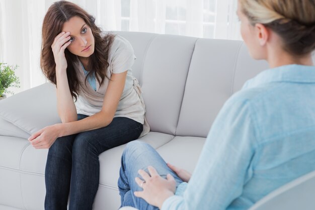 Donna sconvolta seduto sul divano e guardando terapeuta