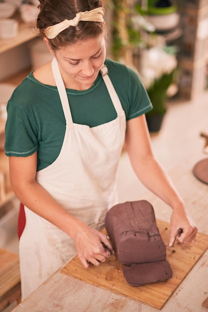 Donna scultrice ha tagliato l'argilla e il tavolo in officina per lo sviluppo della visione artistica o il prodotto in ceramica Design creativo della scultura della signora dell'artista o materiale organico naturale in studio per la creatività alla scrivania