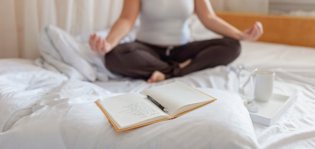 Donna sdraiata a letto meditando accanto al diario o al taccuino