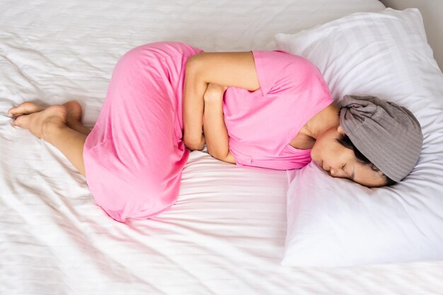 Donna sdraiata sul letto e con le mani sullo stomaco