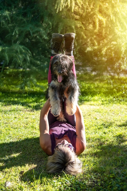 Donna sdraiata sull'erba che alleva il suo amato cane da pastore catalano Amore per gli animali Sport con animali domestici