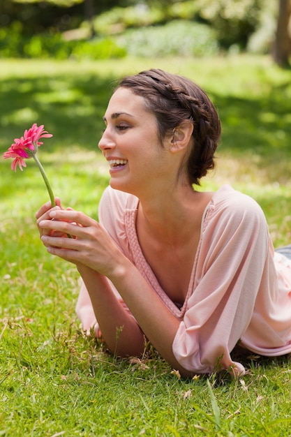 Donna sdraiata sulla sua fronte ridendo mentre guardando un fiore