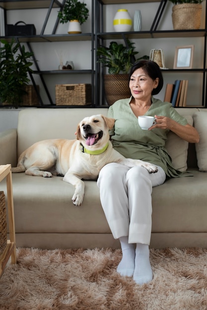 Donna seduta a casa sul divano con una tazza di caffè accanto al suo cane