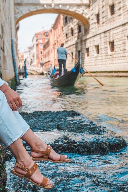 Donna seduta al molo della città di venezia italia godendo della vista dei canali con le gondole