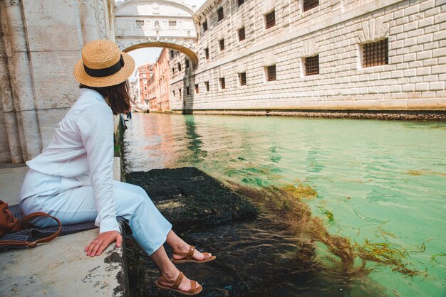 Donna seduta al molo della città di venezia italia godendo della vista dei canali