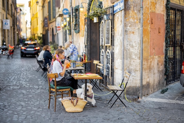 Donna seduta al ristorante tradizionale sulla bellissima e accogliente strada di Roma