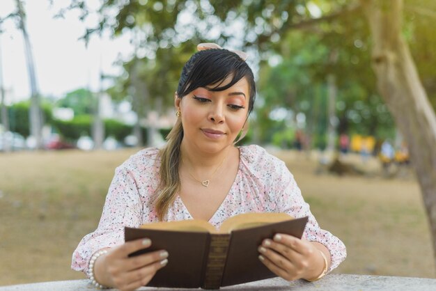 Donna seduta al tavolo di un parco a leggere un libro Giornata mondiale del libro Concetto di lettura